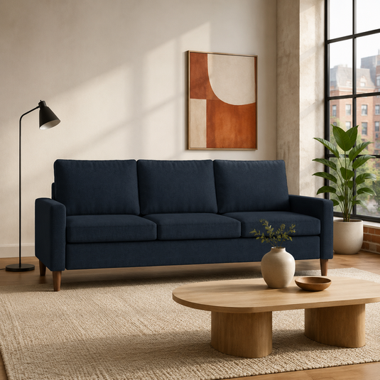 Dark navy three-seat sofa styled in a warm contemporary American apartment living room.